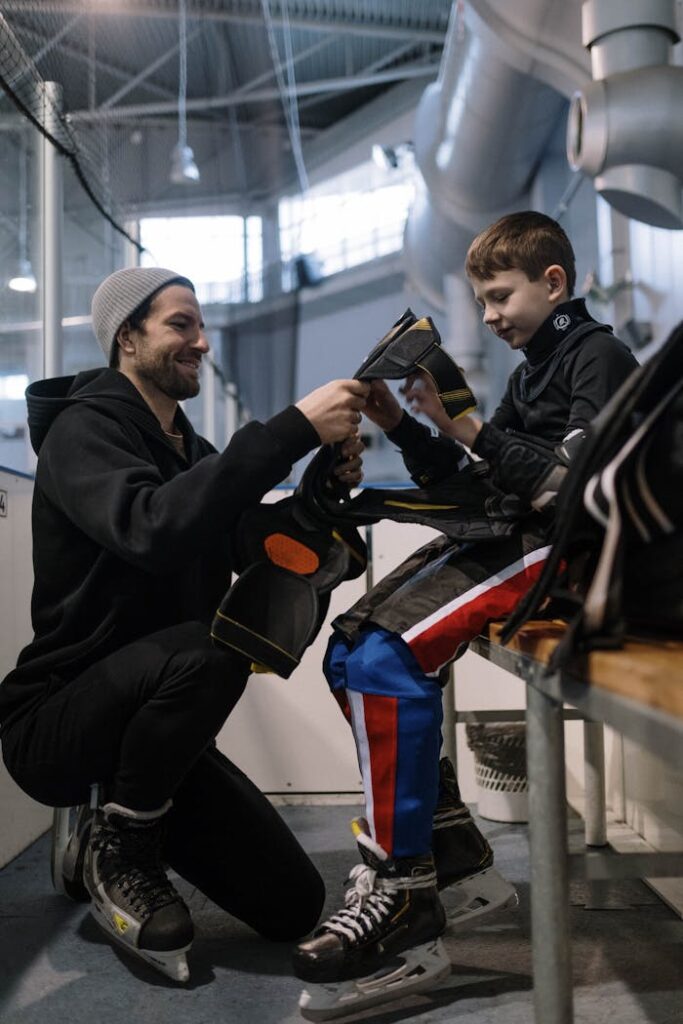 A Man Helping a Boy Wear Ice Hockey Sports Gear