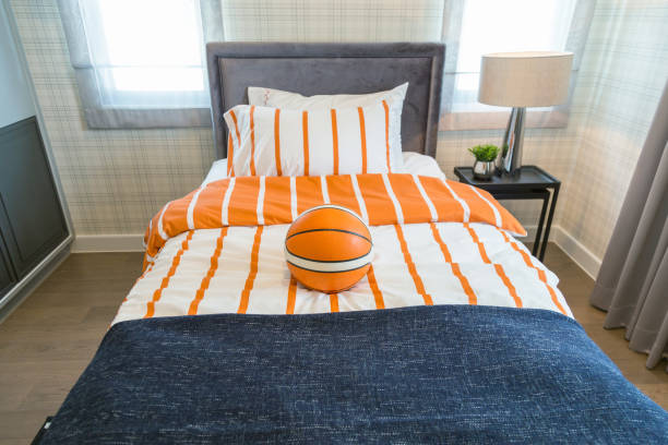 A basketball on the bed with bedside lamp in bedroom kids with warm light.