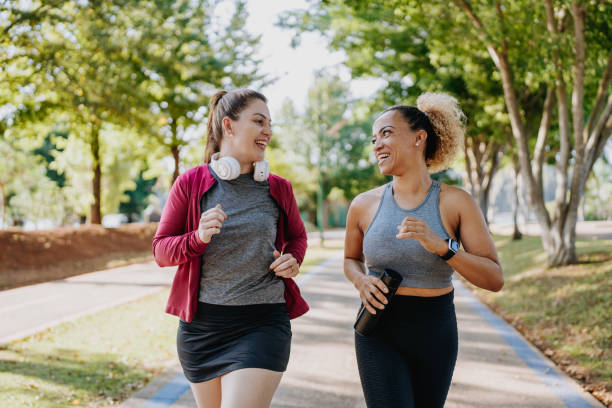 Two fitness women friends running nature public park