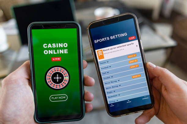 A close-up shot of an unrecognisable man and woman sitting indoors, they are holding smart phones in their hand and they are using them to gamble in an online casino and sports bet online.