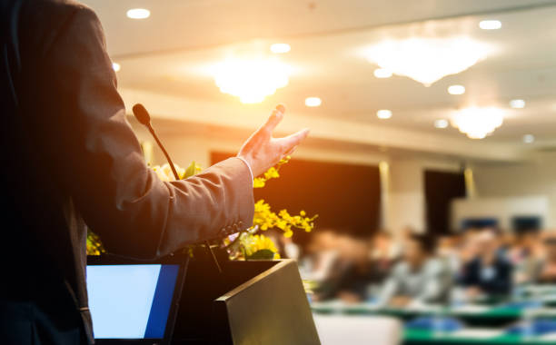 Business man making a speech in front of audience at conference hall.